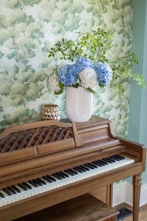 Um piano de cauda com um vaso decorativo de flores em cima.