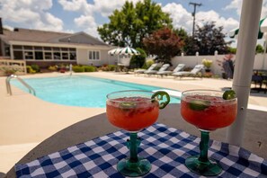 Two cocktails on a checkered tablecloth by a poolside with lounge chairs and umbrellas in the background. - The Pearl Retreat (Nashville)