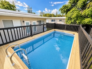A rectangular swimming pool with a wooden deck and metal handrails, surrounded by a black fence. - King Retreat with Pool near Miami Beach (Miami)