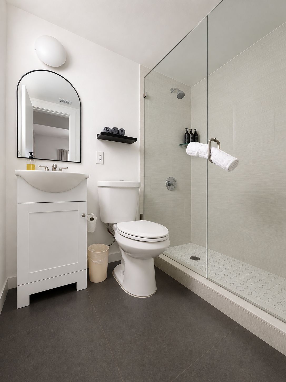 A modern bathroom with a white sink, toilet, and shower area.
