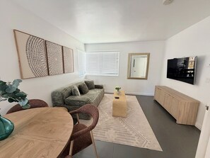 A modern living room with a sofa, a coffee table, a TV, and a dining area with chairs. - King Retreat with Pool near Miami Beach (Miami)