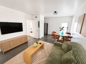 A modern living room with a flat-screen TV, a sofa, a coffee table, and a dining area with a table and chairs. - King Retreat with Pool near Miami Beach (Miami)