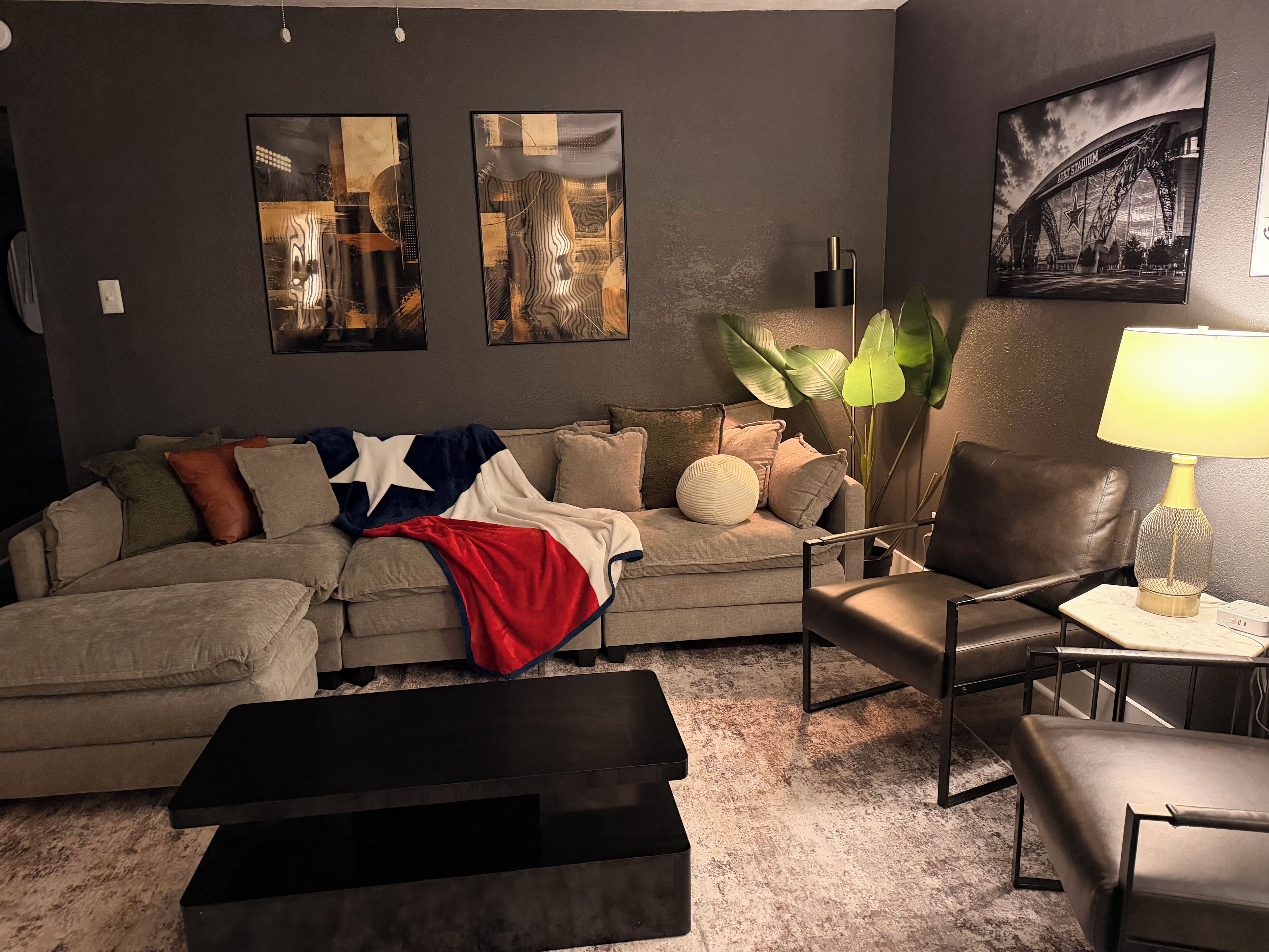 A living room with a sofa, a coffee table, a lamp, and artwork on the wall.