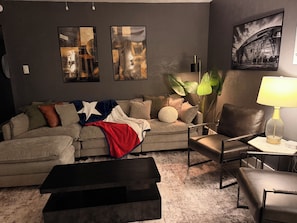 Un salon avec un canapé, une table basse, une lampe et des œuvres d’art accrochées au mur.