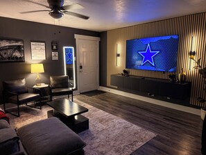 A modern living room with a flat-screen TV, leather chairs, a coffee table, and a decorative star on the wall. - Destino Stadium Suite 428 (Arlington)