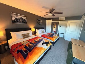 A hotel room with two beds, a ceiling fan, a desk, and a door. - Destino Stadium Suite 428 (Arlington)