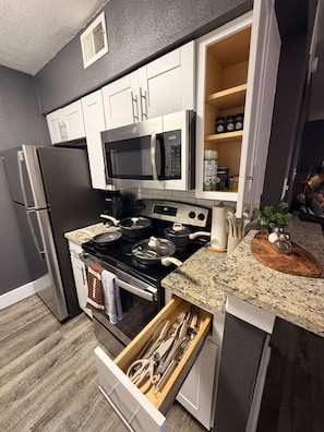 A modern kitchen with stainless steel appliances, a granite countertop, and a built-in oven. - Destino Stadium Suite 428 (Arlington)