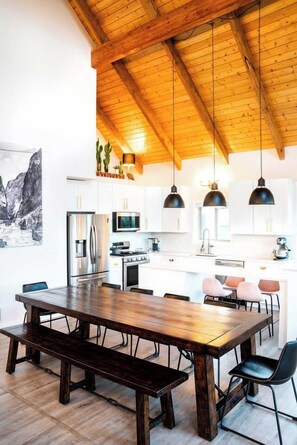 Una cucina moderna con travi in legno, elettrodomestici in acciaio inossidabile e lampade a sospensione.