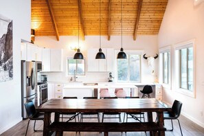 Una cucina moderna con mobili bianchi, un tavolo da pranzo in legno e lampade a sospensione.