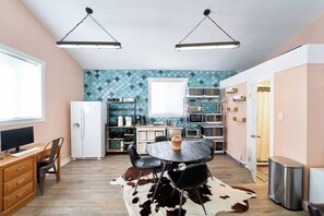 A compact kitchen with a dining area, a refrigerator, a microwave, and a coffee machine.