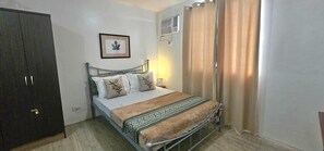 A bedroom with a bed, a wardrobe, a picture on the wall, and a window with curtains.