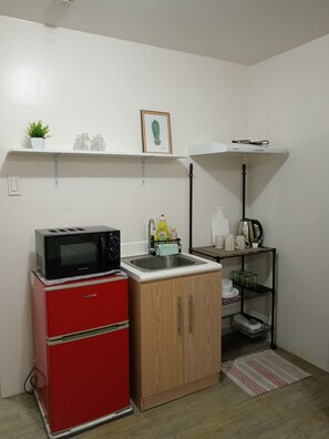 A compact kitchen with a red refrigerator, a microwave, a sink, and a small cabinet.