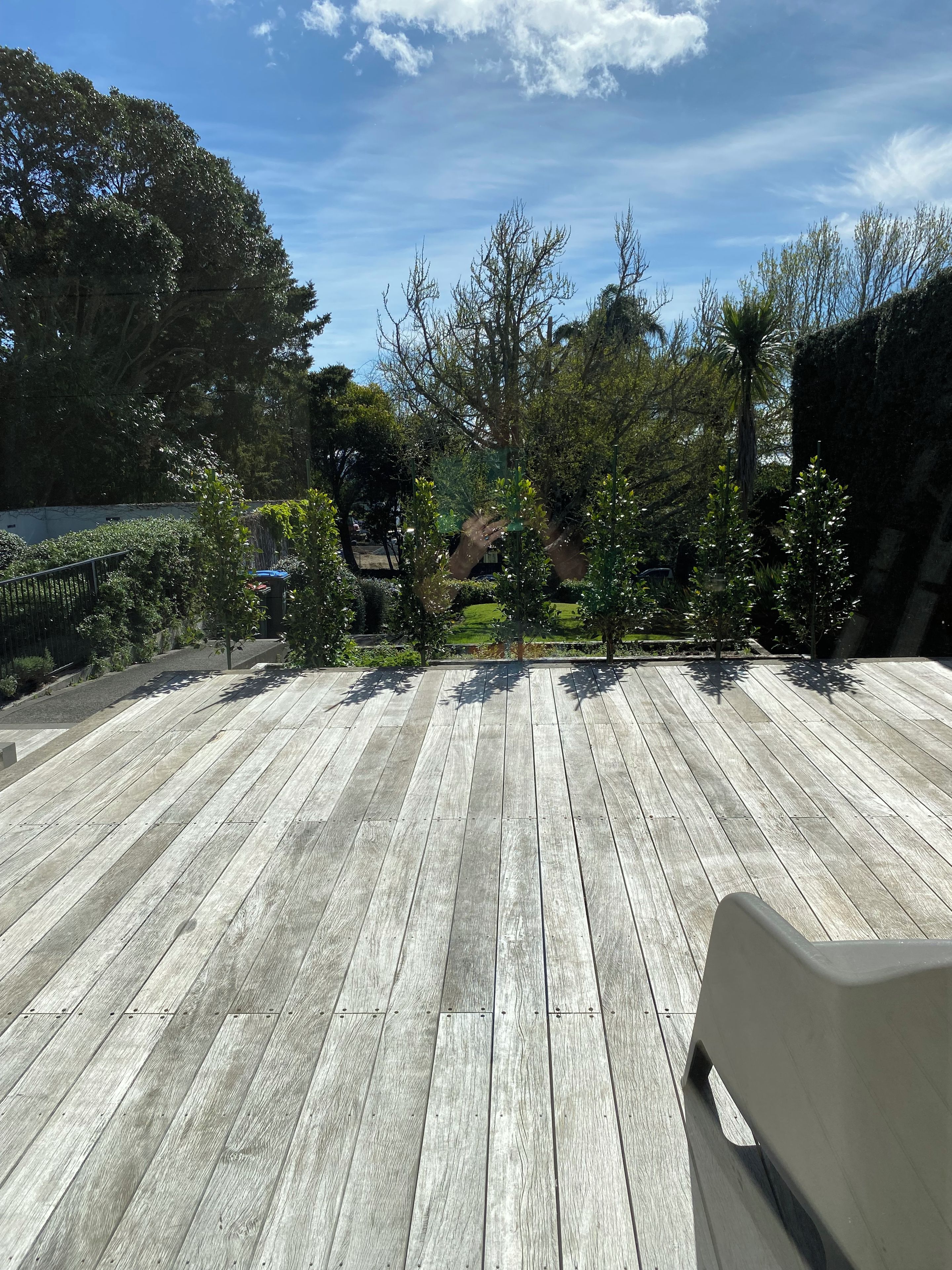 A wooden deck with a view of a garden and trees.