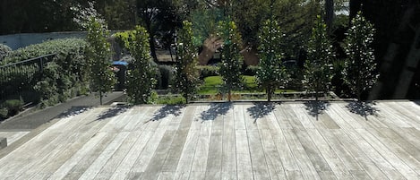 Un terrazzo in legno con vista su un giardino e alberi.