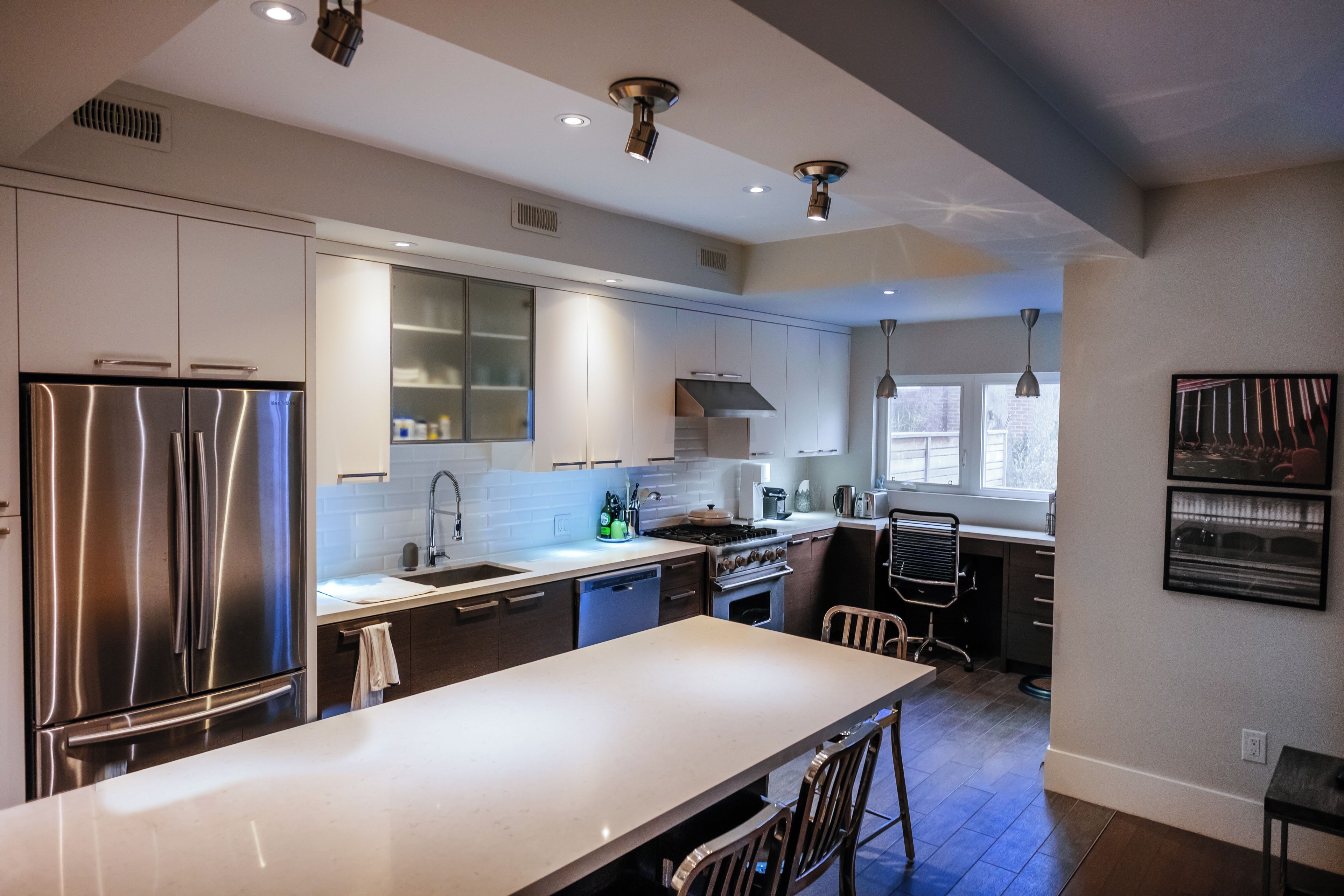 A modern kitchen with stainless steel appliances, a large island, and a dining area.