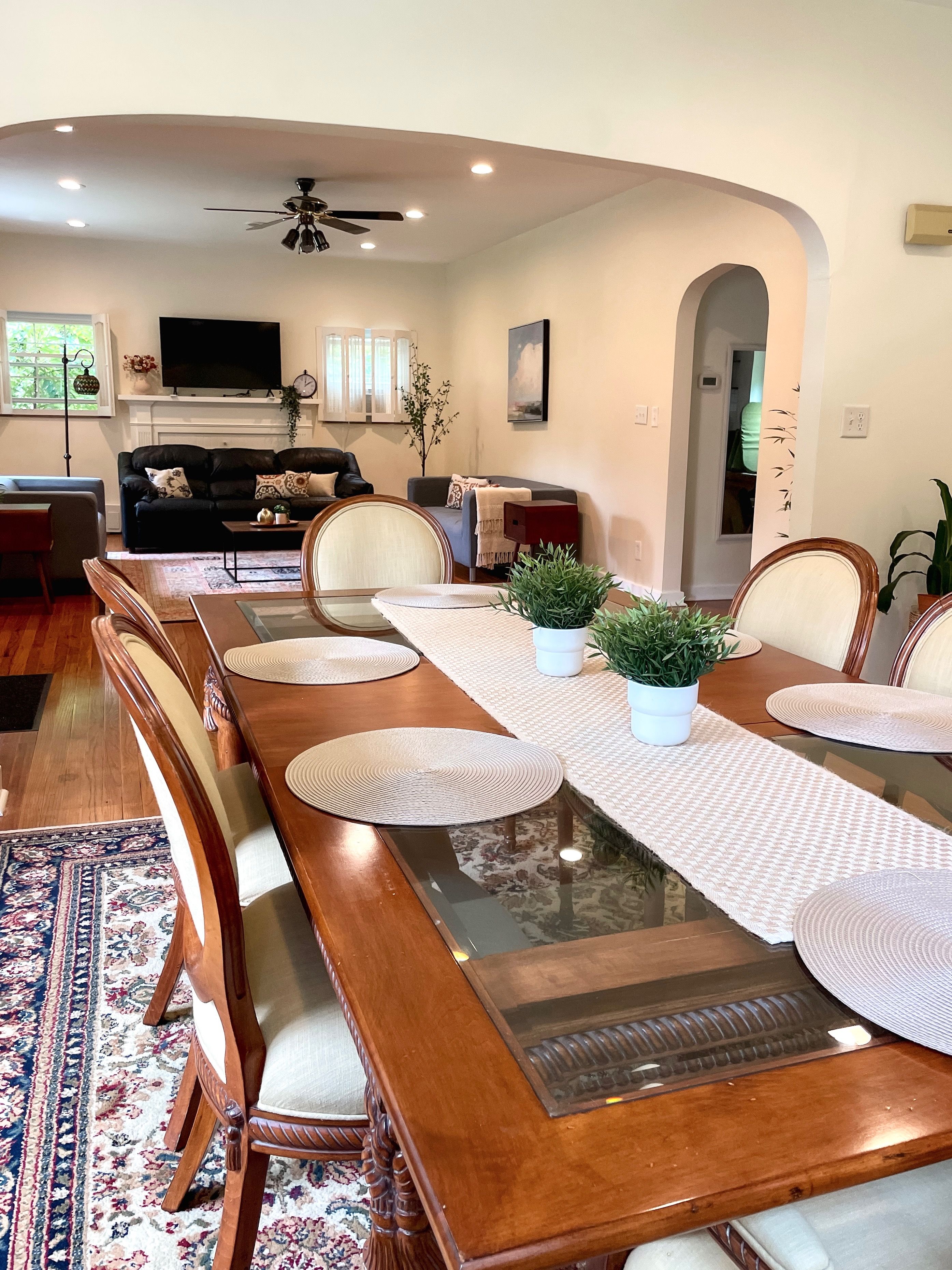 A dining area with a long wooden table, chairs, and a central plant.