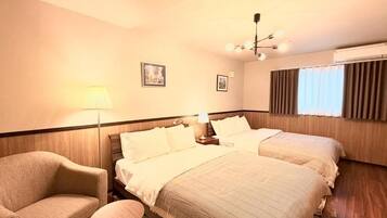 A hotel room with two beds, a sofa, a small table, and a ceiling light fixture.
