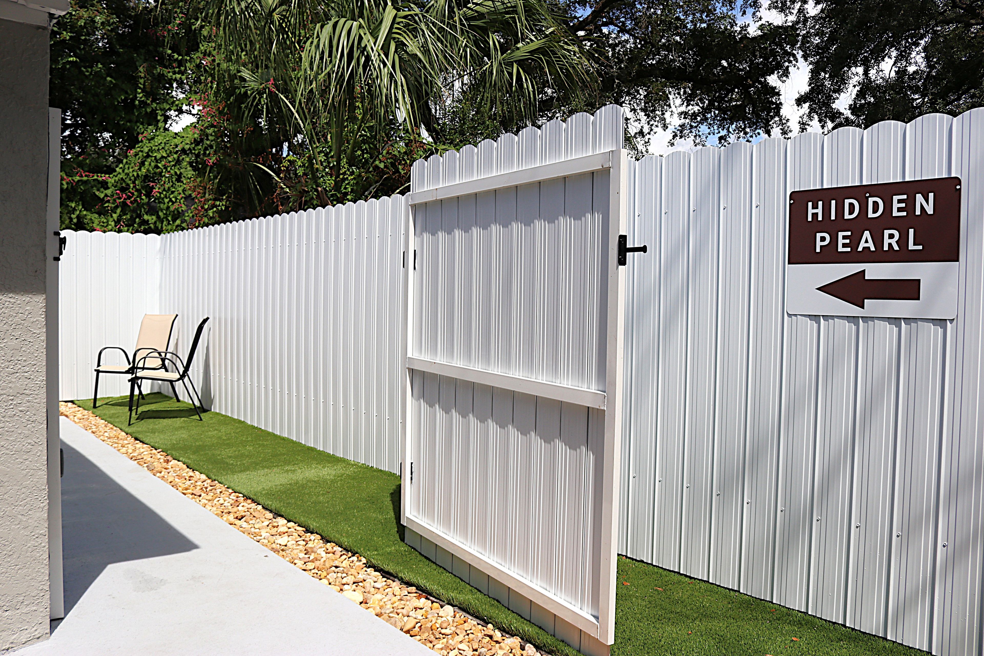 A white fence with a sign indicating 'Hidden Pearl' and an arrow pointing to the left.