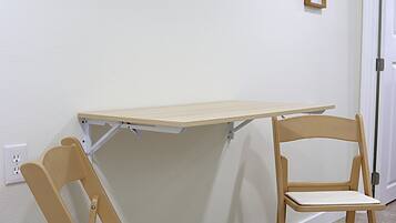 A room with a small table and two chairs, a wall-mounted decorative piece, and a door.