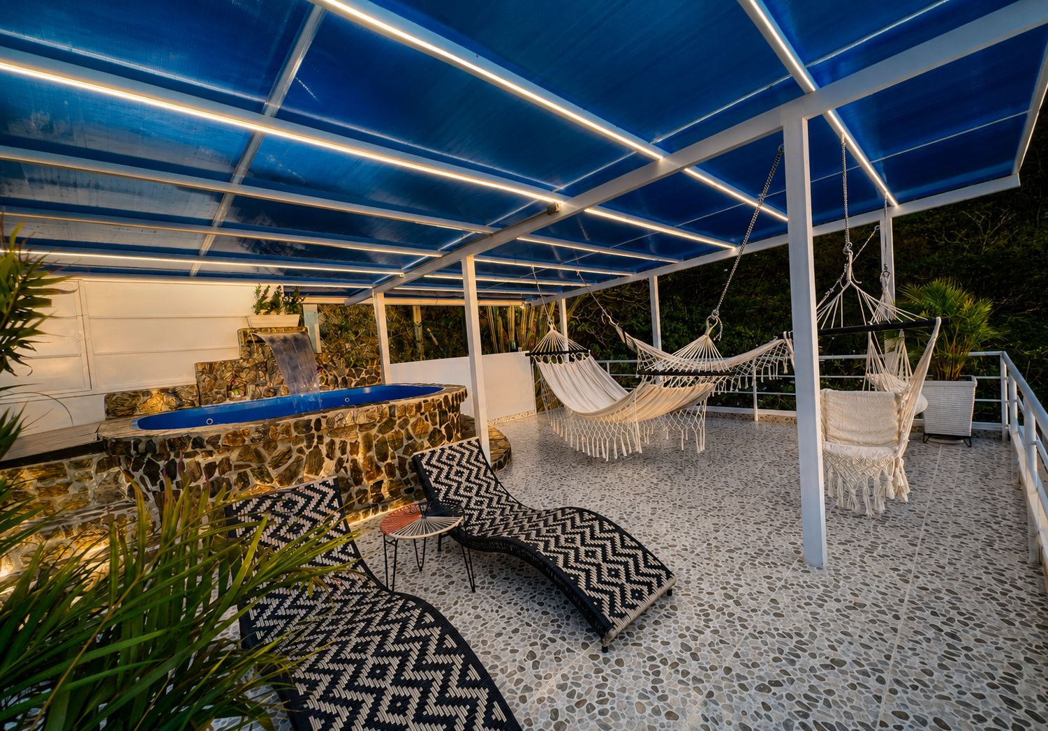 An outdoor patio with a stone pool, hammocks, and patterned seating.
