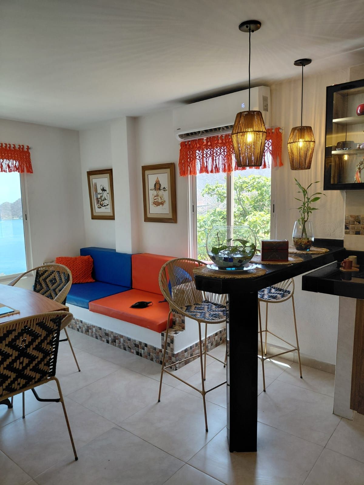 A modern kitchen with a dining area, a sofa, and a view of the outdoors.