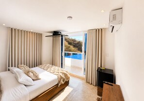 Un dormitorio con cama, cortinas, puerta de vidrio corredera a un balcón y chimenea.
