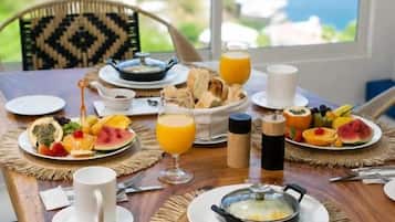 Ein Frühstückstisch mit Speisen, einer Tasse und einem Glas Orangensaft, mit Blick auf das Meer.