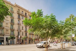 A street view with a row of buildings, a parked car, and a pedestrian crossing. - GuestReady - Eixample Retreat (Barcelona)