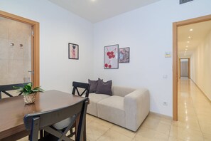 A modern living room with a sofa, a dining table, and chairs. There are framed artworks on the wall. - GuestReady - Eixample Retreat (Barcelona)