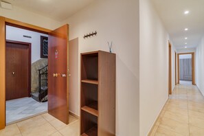 A hallway with a wooden door labeled 'principal,' a coat rack, and a staircase. - GuestReady - Eixample Retreat (Barcelona)