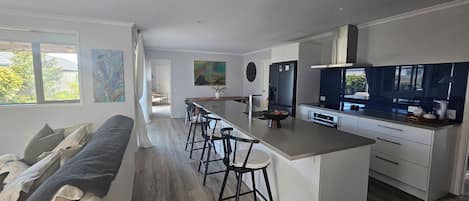 A modern kitchen with a central island, bar stools, and a built-in oven.