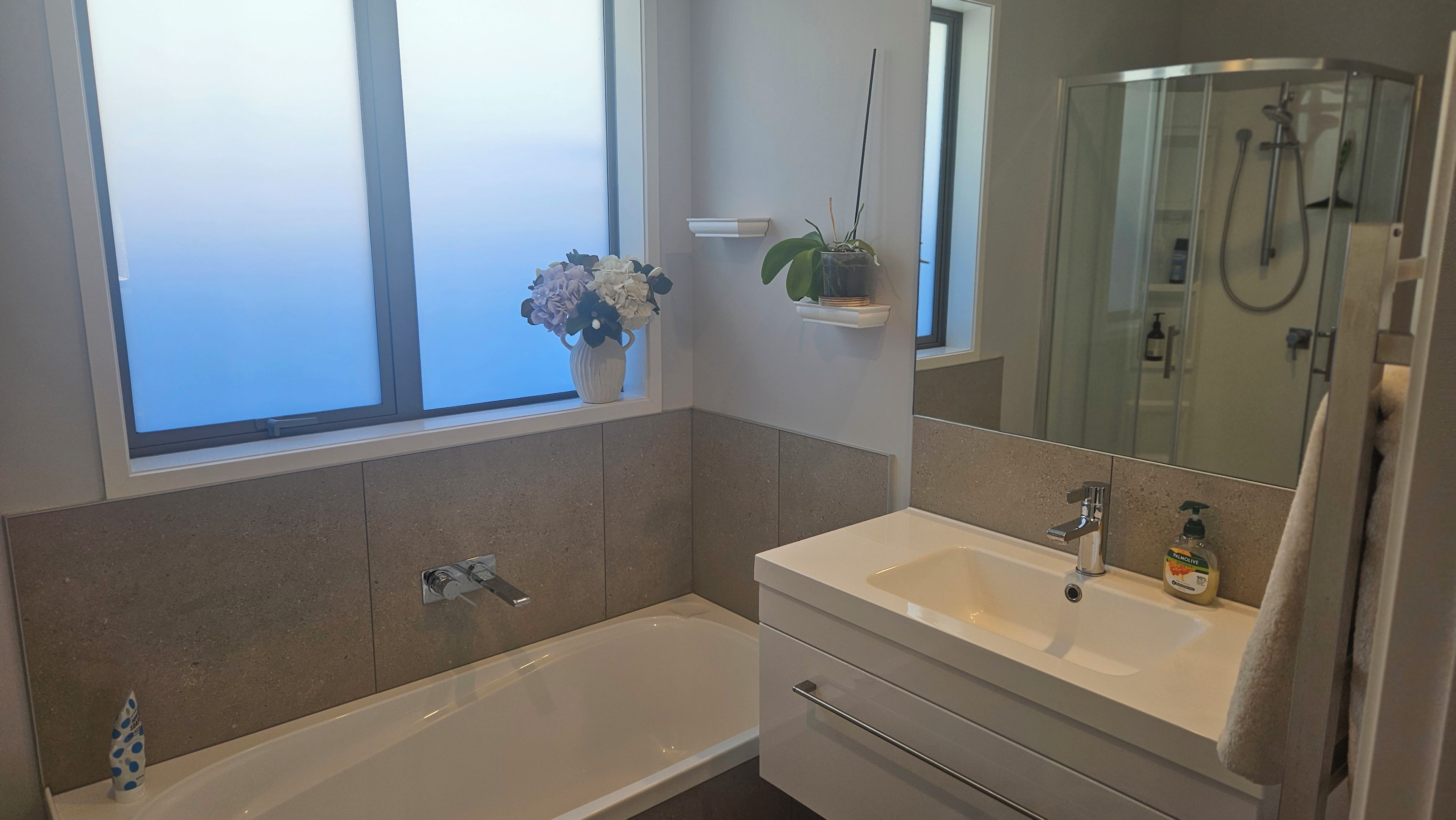 Een moderne badkamer met een bad, een wastafel, een spiegel en een douche.