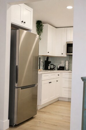 A modern kitchen with white cabinetry, a stainless steel refrigerator, and a microwave. - Prime Tampa Bay Stay | Stadium, Midtown & Downtown (Tampa)