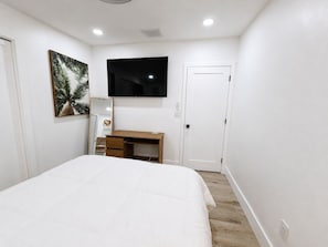 A bedroom with a bed, a desk, a TV, and a door. - Prime Tampa Bay Stay | Stadium, Midtown & Downtown (Tampa)