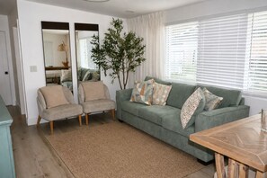 A living room with a sofa, two armchairs, a coffee table, and a large mirror. - Prime Tampa Bay Stay | Stadium, Midtown & Downtown (Tampa)