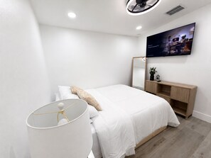 A modern bedroom with a bed, bedside lamp, and a flat-screen TV mounted on the wall. - A First-Class Stay in Tampa Bay | Stadium, Midtown, and Downtown (Tampa)