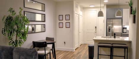 A modern kitchen with a stainless steel refrigerator, a bar counter, and a dining area with a table and chairs.
