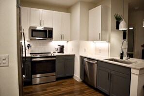 A modern kitchen with stainless steel appliances, white cabinetry, and a wooden floor. - The Luxe Oasis, Resort Pool, Near Grandscape & The Star (Lewisville)