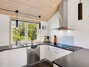 A modern kitchen with a window, stainless steel appliances, and a wooden ceiling. - "Fokke" - 900m from the sea by Interhome (Løkken)