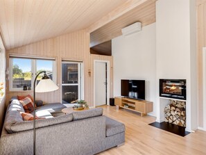 Ein modernes Wohnzimmer mit einem grauen Sofa, einem Fernseher und einem Kamin.