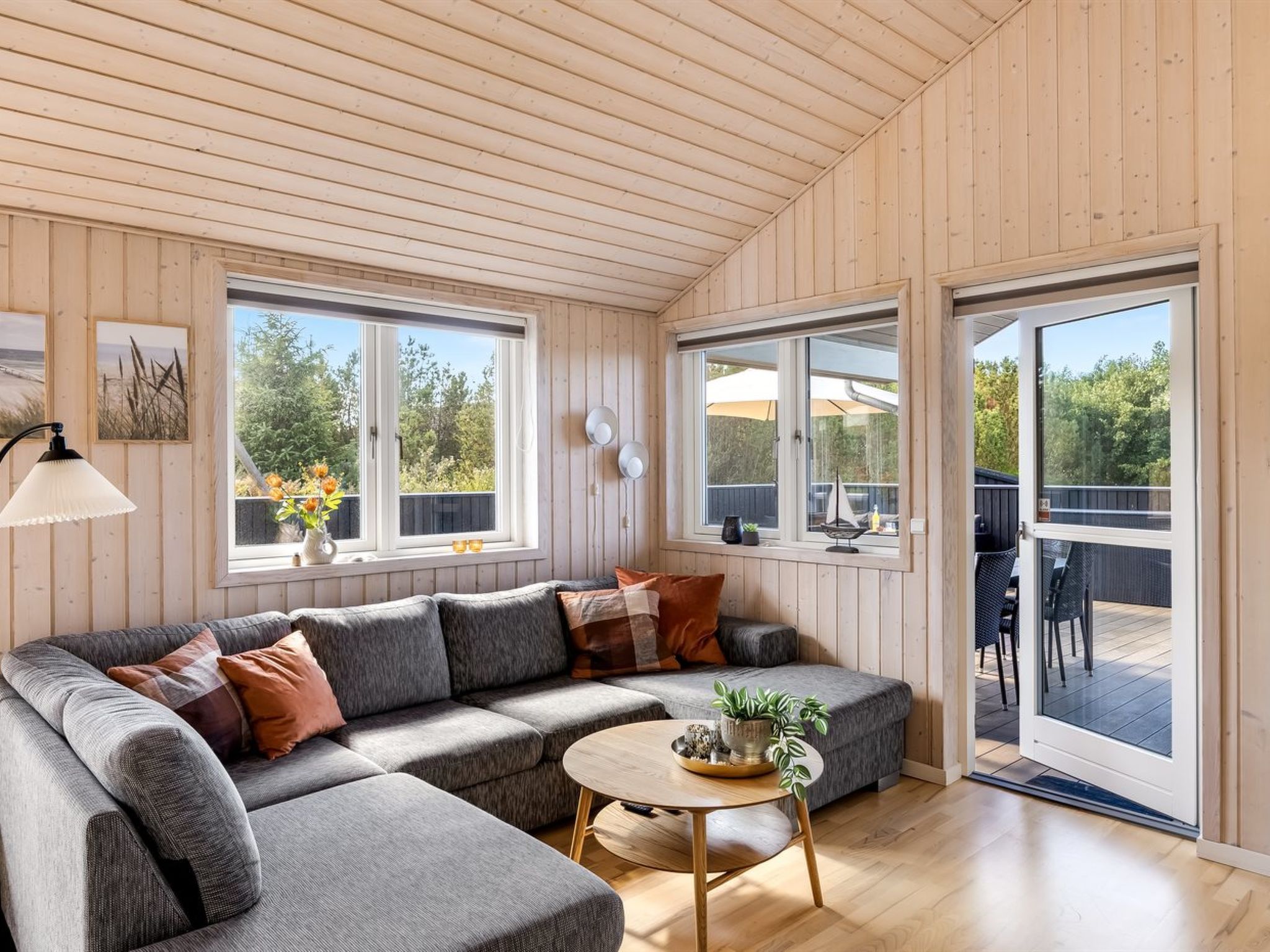 A modern living room with a sectional sofa, a small round table, and large windows offering views of the outdoors.