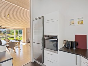 A modern kitchen with a built-in oven, a refrigerator, and a coffee maker on the counter. - "Fokke" - 900m from the sea by Interhome (Løkken)