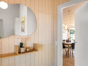 A wooden interior with a curved mirror, a small shelf with a plant, and a dining area visible through an open door. - "Fokke" - 900m from the sea by Interhome (Løkken)