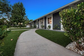 Une maison moderne à deux étages, avec une allée en béton menant à la porte d’entrée.