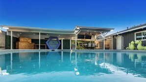 Una piscina amb una zona coberta, una estructura de fusta i un cartell que diu 'Tommy Bahama'.