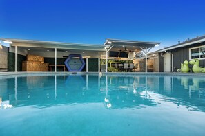 Une piscine dotée d’une zone couverte, d’une structure en bois et d’un panneau indiquant « Tommy Bahama ».