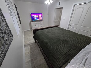 A bedroom with a bed, a dresser, a television, and a door. - Serene 3-bedroom house with AC in charming Chandler (Chandler)
