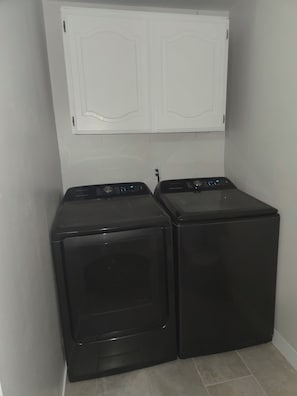 A laundry room with two black washing machines and a white double door above them. - Serene 3-bedroom house with AC in charming Chandler (Chandler)