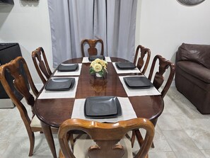 A dining table with eight chairs, a vase with yellow flowers, and placemats. - Serene 3-bedroom house with AC in charming Chandler (Chandler)