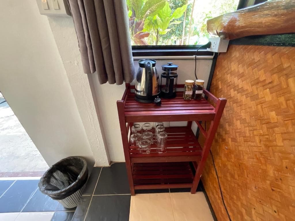 A wooden shelf with a coffee maker, jars, and glasses.
